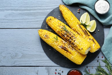 Flat lay composition with tasty grilled corn on light blue wooden table. Space for text