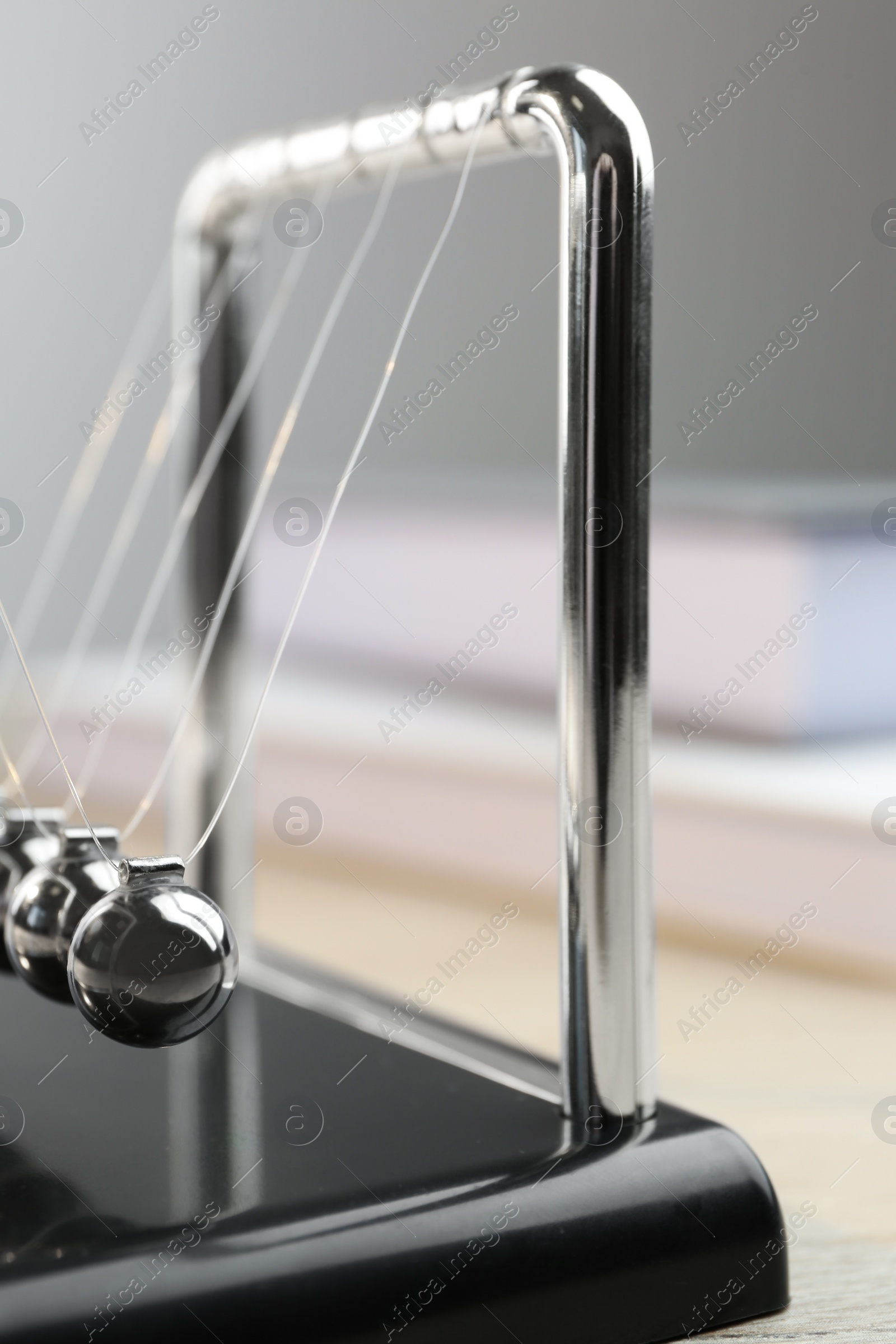 Photo of Newton's cradle on wooden table, closeup. Physics law of energy conservation