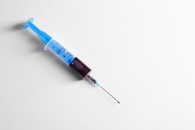 Plastic syringe with blood on white background
