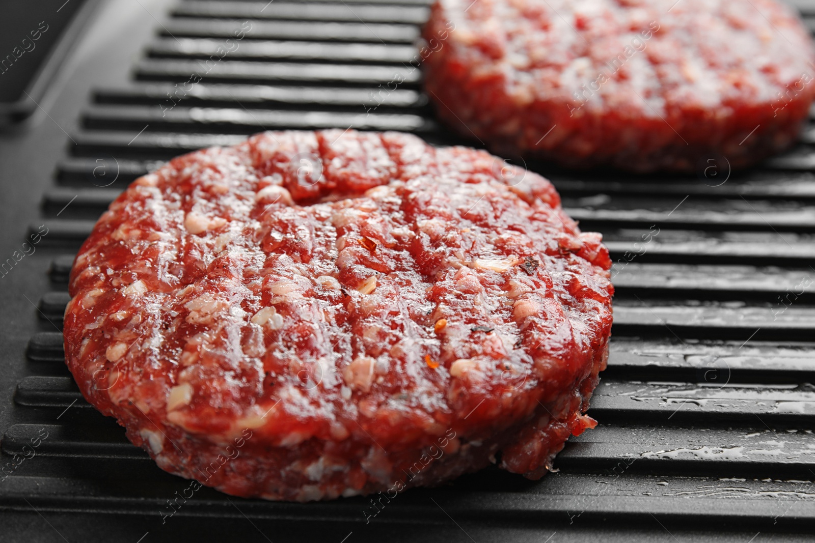Photo of Raw meat cutlets for burger on grill, closeup