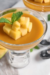 Photo of Delicious panna cotta with mango coulis and fresh fruit pieces on table, closeup