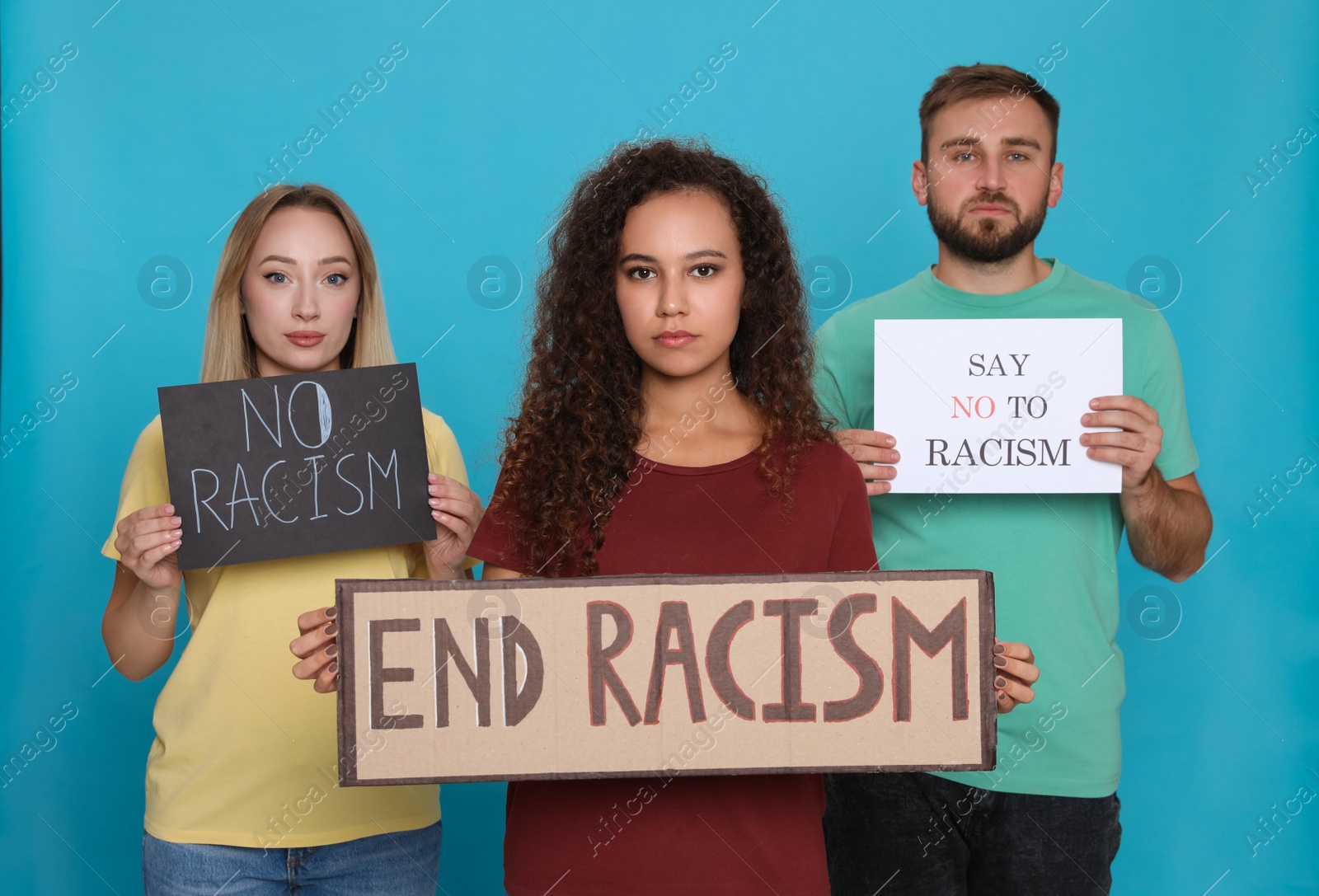 Photo of Group of people holding signs on light blue background. Racism concept