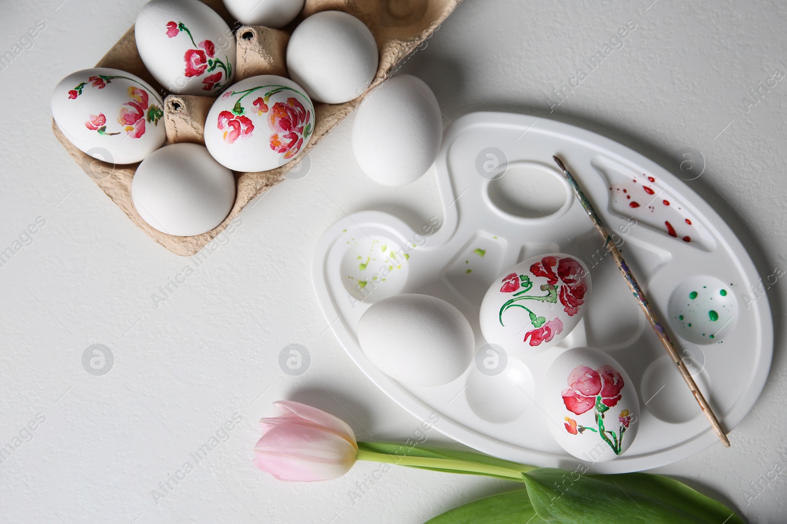 Photo of Painting Easter eggs on white table, flat lay