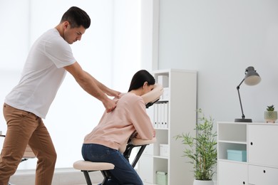 Woman receiving massage in modern chair indoors