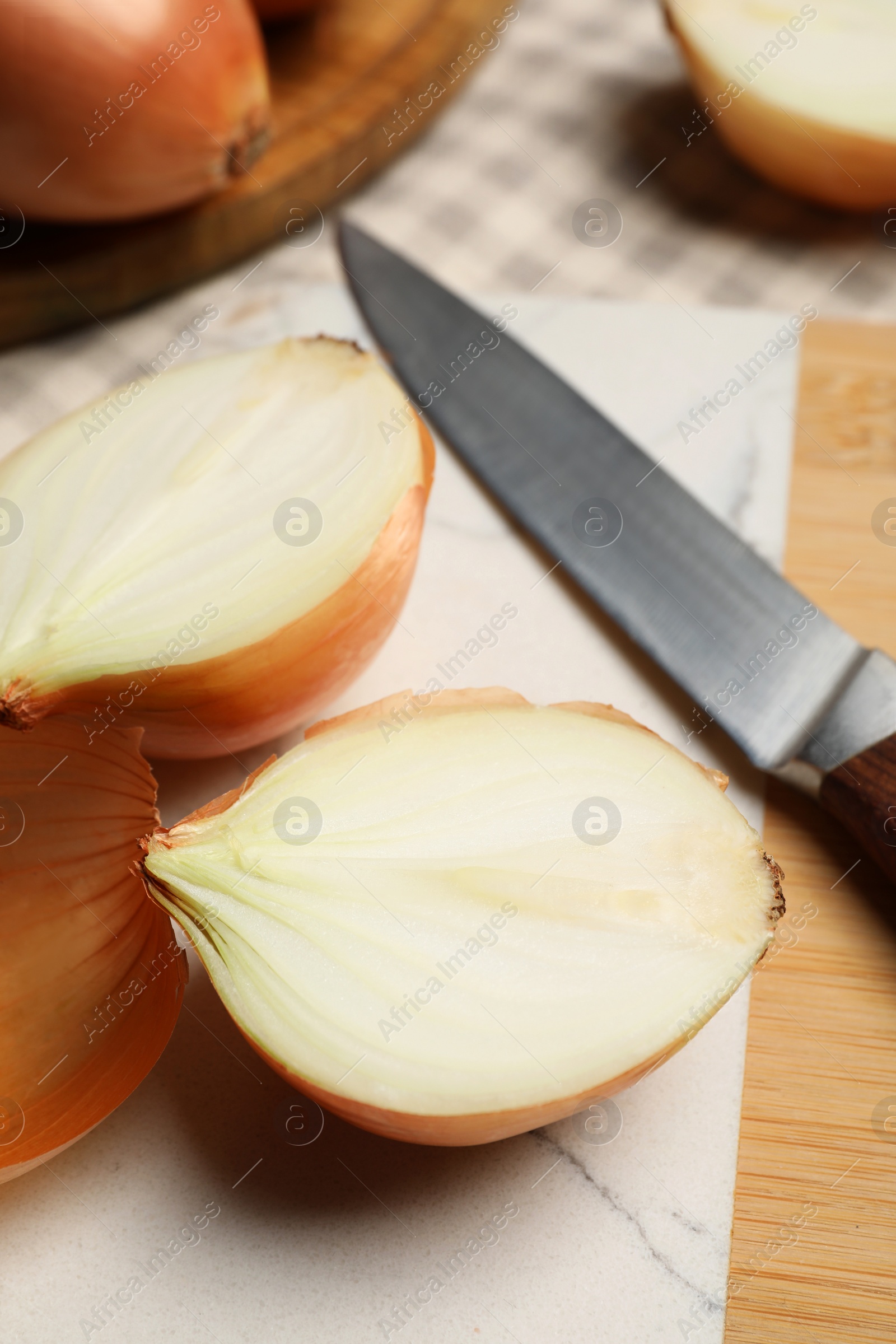 Photo of Whole and cut onions with knife on table, closeup
