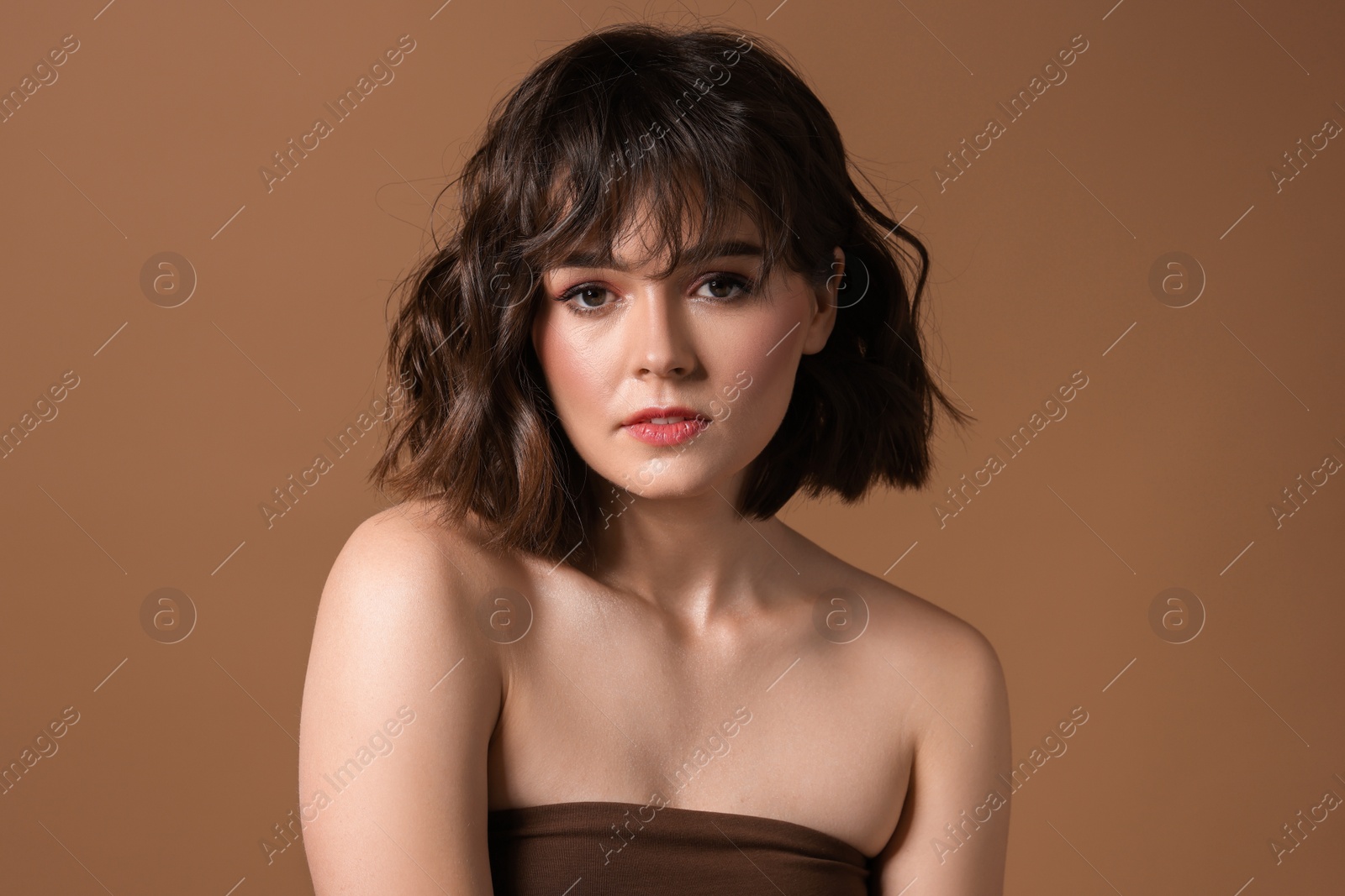 Photo of Portrait of beautiful young woman with wavy hairstyle on brown background