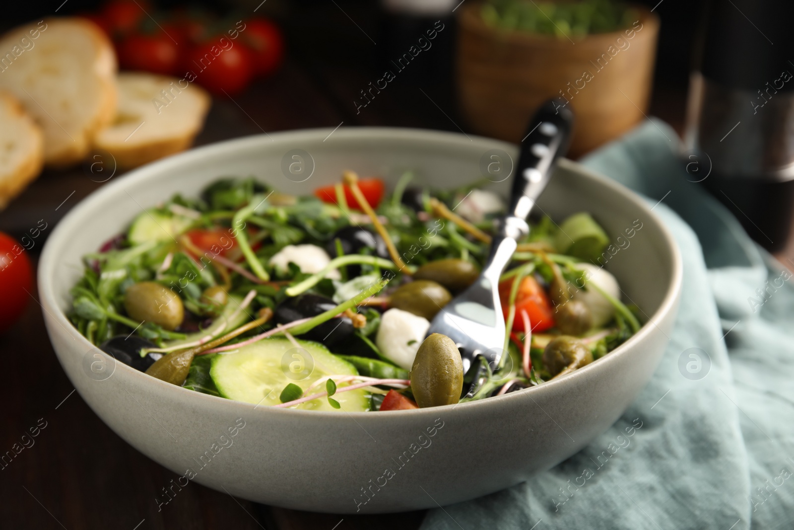 Photo of Fresh salad with vegetables, capers and mozzarella in bowl, closeup