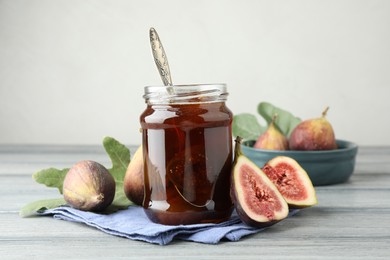 Photo of Jar of tasty sweet jam and fresh figs on grey table