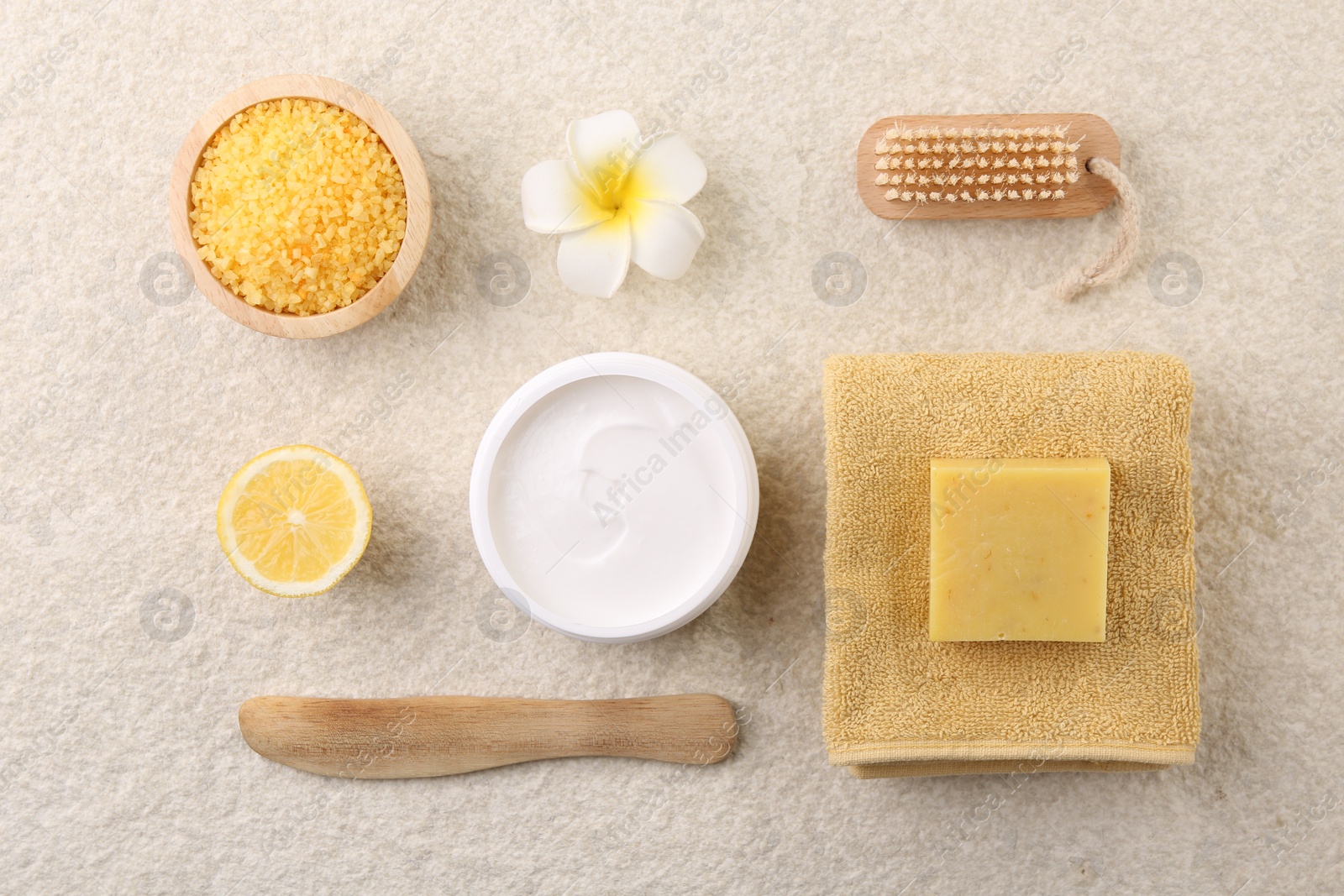 Photo of Flat lay composition with moisturizing cream in open jar and other body care products on light textured table