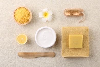 Flat lay composition with moisturizing cream in open jar and other body care products on light textured table