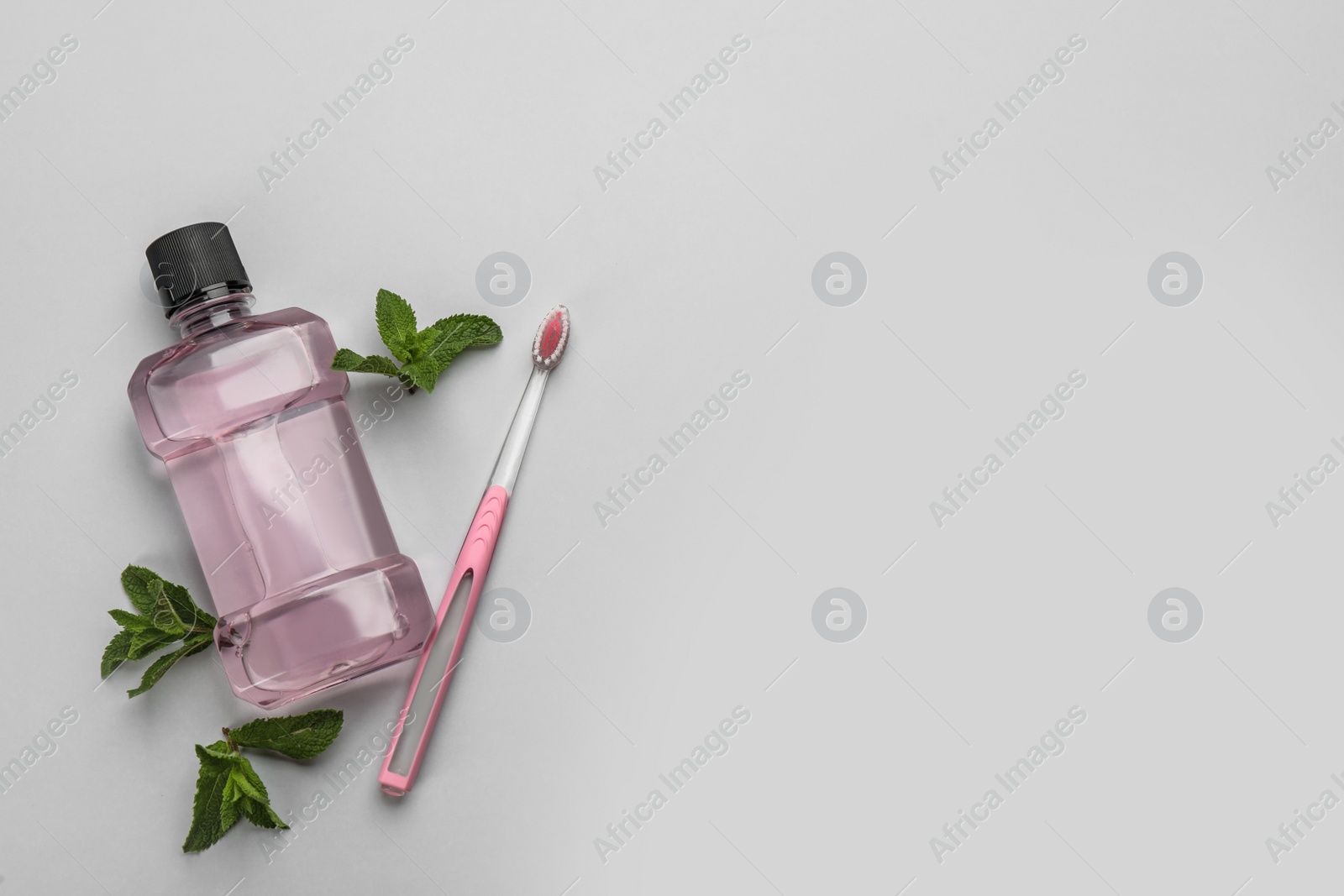 Photo of Mouthwash, toothbrush and mint on light grey background, flat lay. Space for text