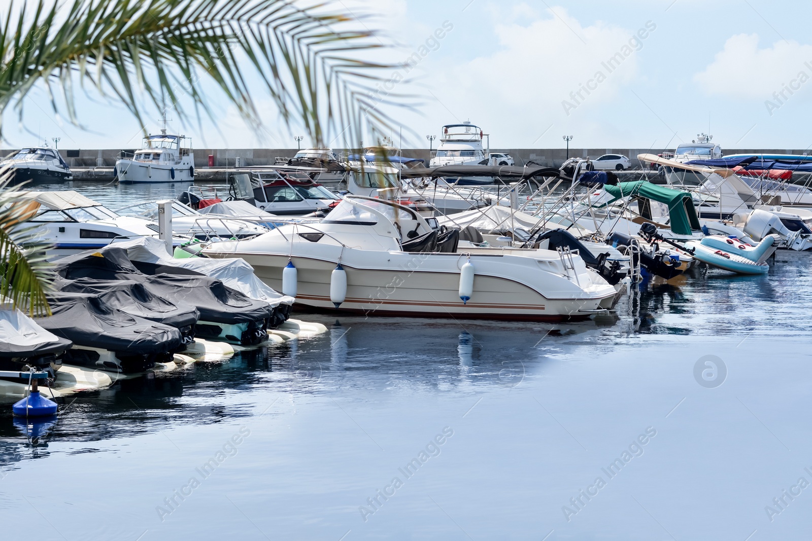 Photo of Beautiful view of city pier with moored boats and water scooters on sunny day