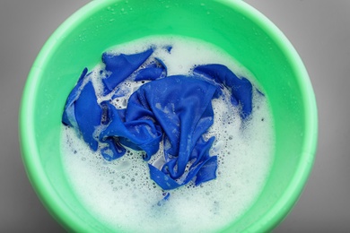 Photo of Color clothes with foam in basin, top view