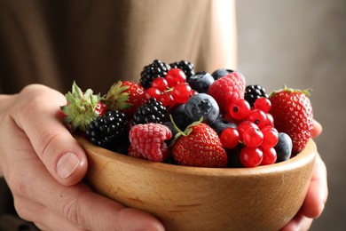 Photo of Woman with bowl of delicious summer berries, closeup