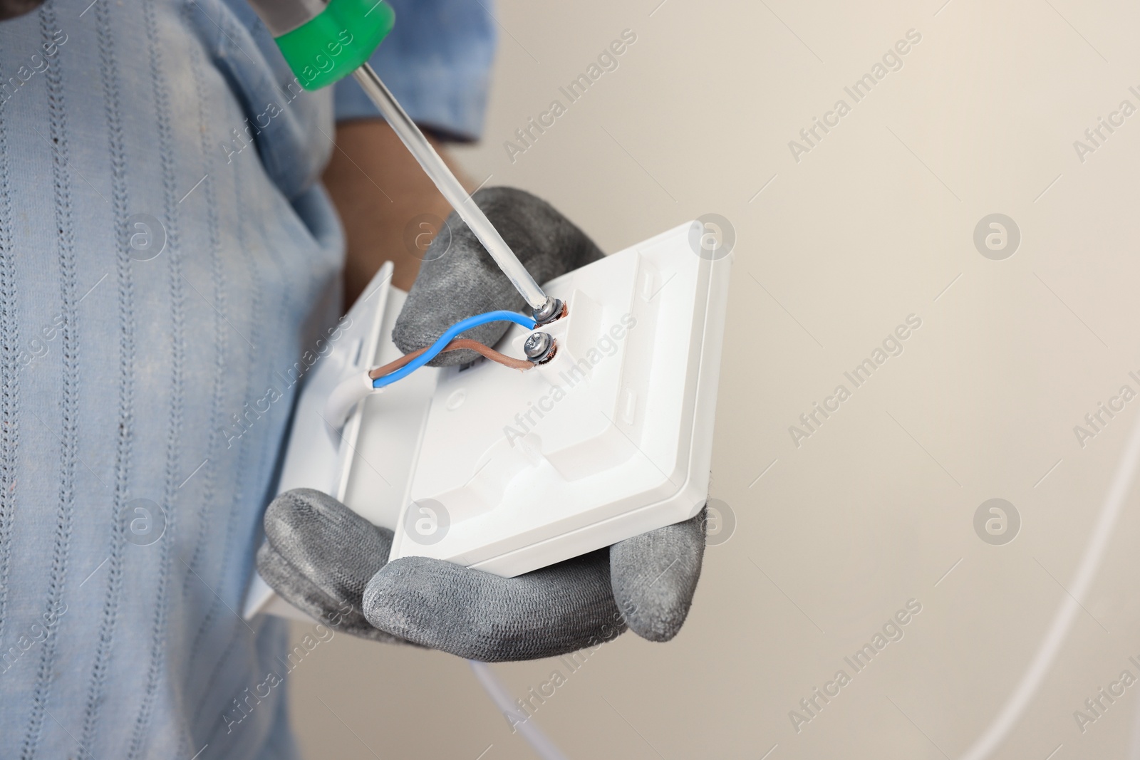 Photo of Electrician with screwdriver installing remote meter indoors, closeup