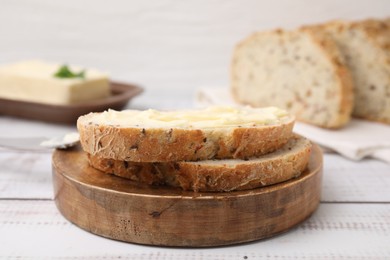 Photo of Slices of tasty bread with butter on white wooden table, closeup