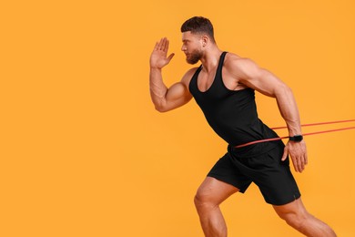 Young man exercising with elastic resistance band on orange background. Space for text