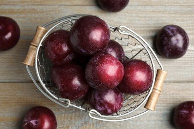 Delicious ripe plums on wooden table, flat lay