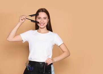 Portrait of happy hairdresser with combs on beige background. Space for text