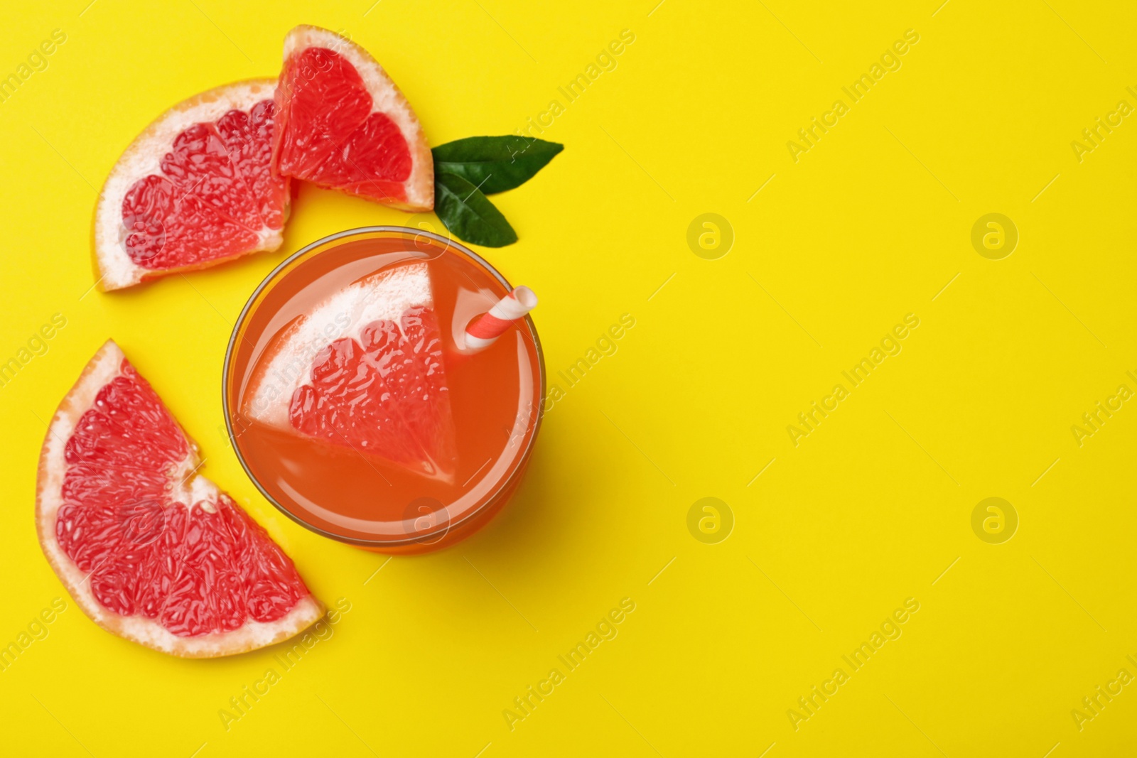 Photo of Tasty freshly made grapefruit juice and fruit on yellow background, flat lay. Space for text