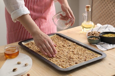 Making delicious baklava. Woman adding chopped nuts to dough at wooden table, closeup