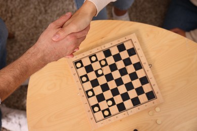 Checkers. Players shaking hands after game indoors, top view