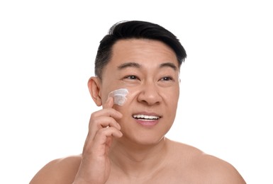 Handsome man applying cream onto his face on white background