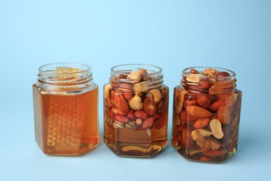 Photo of Jars with different nuts and honey on light blue background