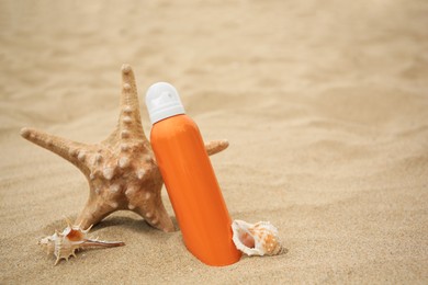 Photo of Sunscreen, starfish and seashells on sand, space for text. Sun protection care