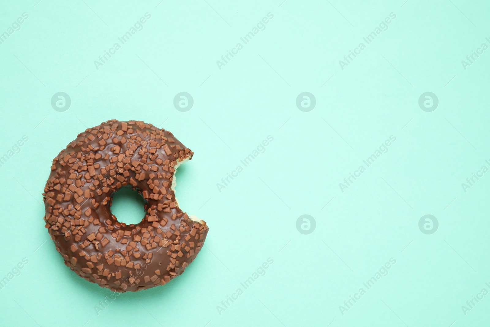 Photo of Delicious glazed donut on turquoise background, top view. Space for text