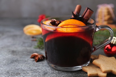 Photo of Aromatic mulled wine, cookies and Christmas decorations on grey table, closeup