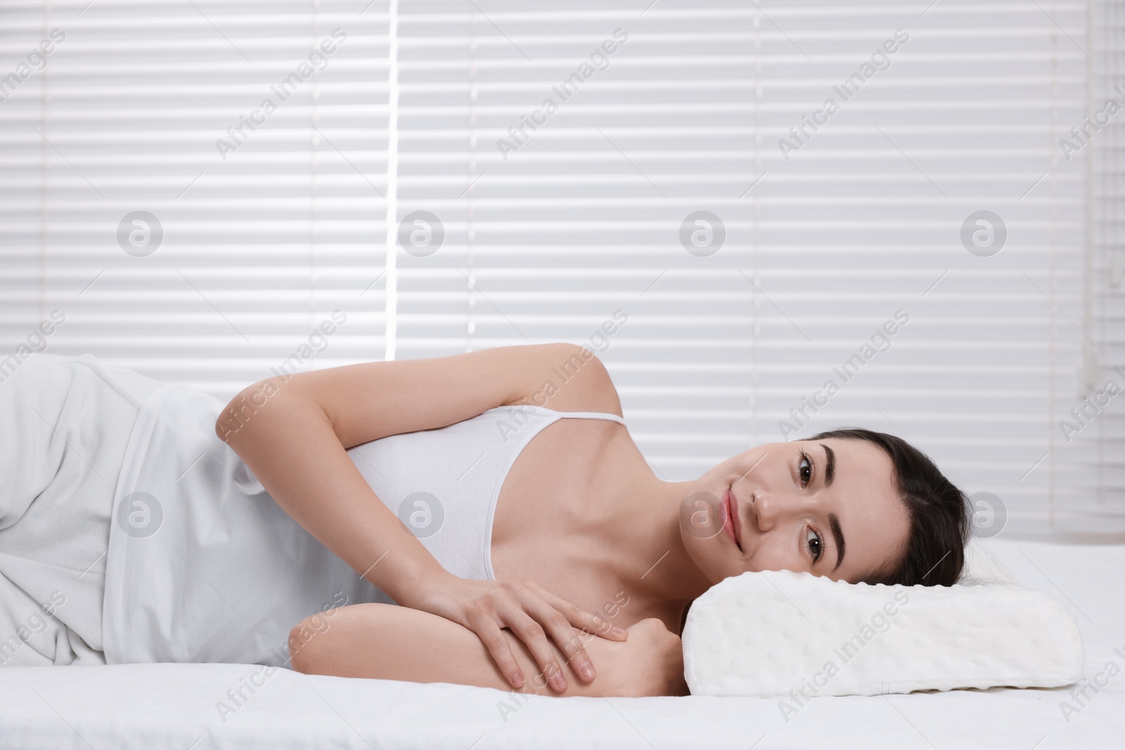 Photo of Woman lying on orthopedic pillow at home