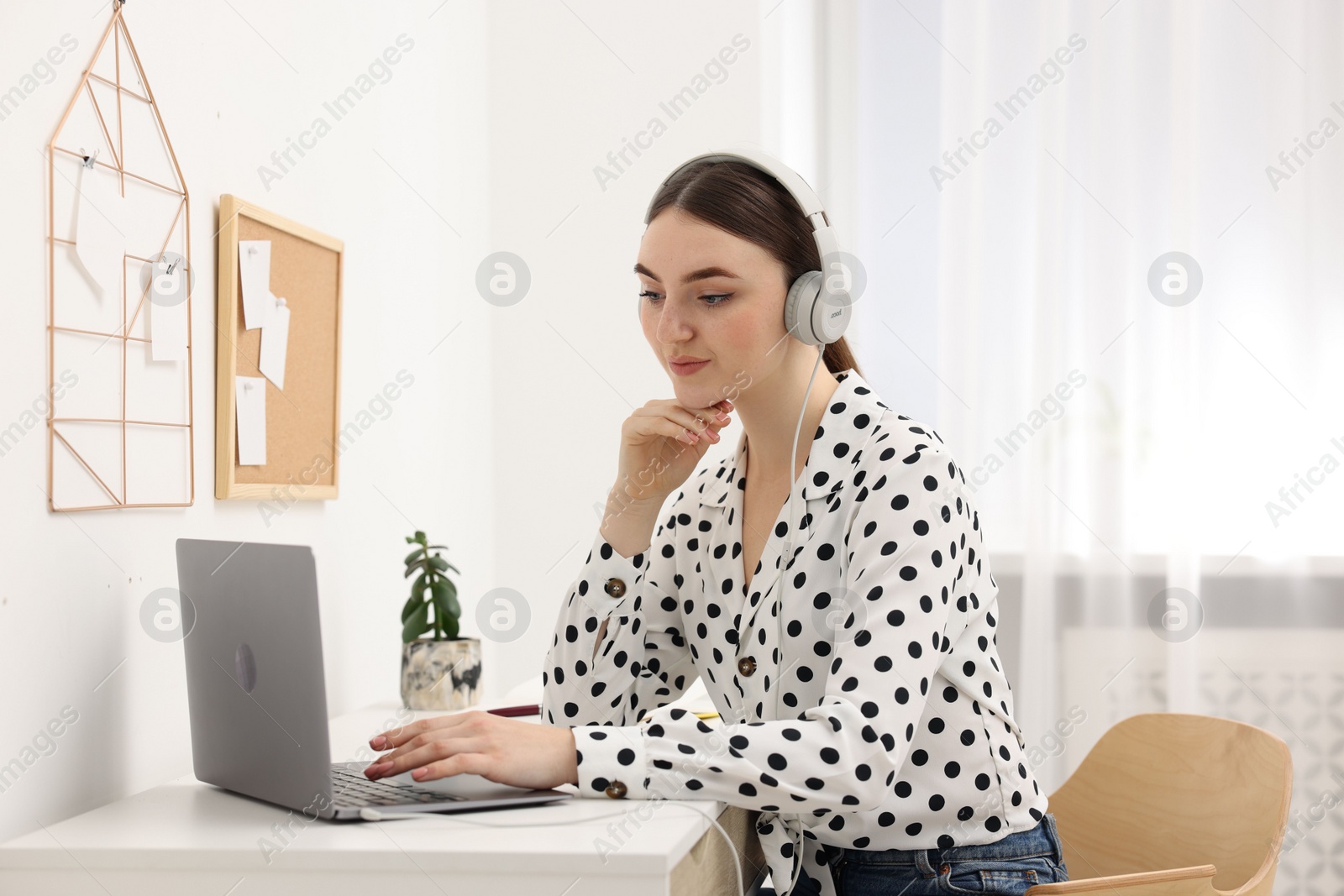 Photo of E-learning. Young woman using laptop during online lesson at table indoors