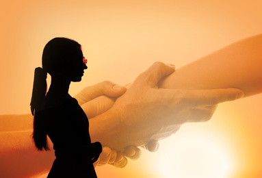 Image of Double exposure with silhouette of young woman and helping hand outdoors at sunset