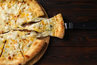 Photo of Delicious cut cheese pizza with server on wooden table, top view