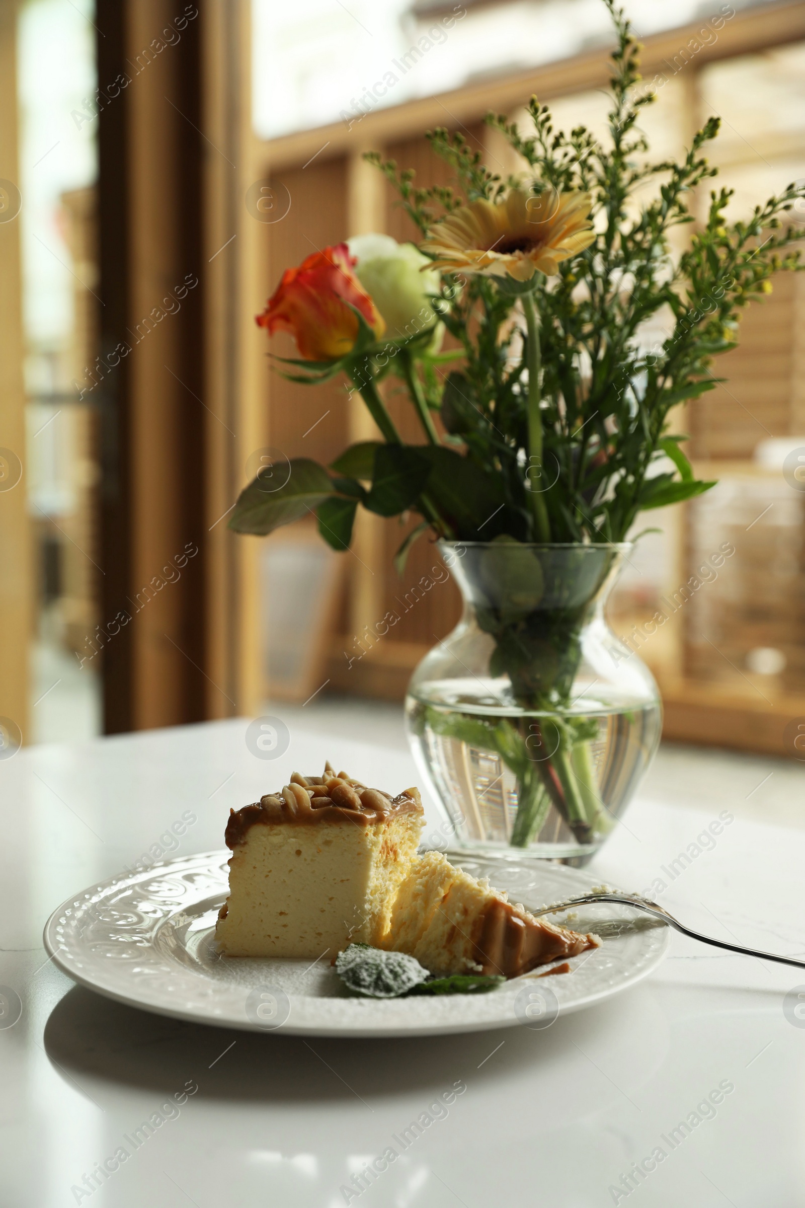 Photo of Tasty dessert and vase with flowers on white table indoors