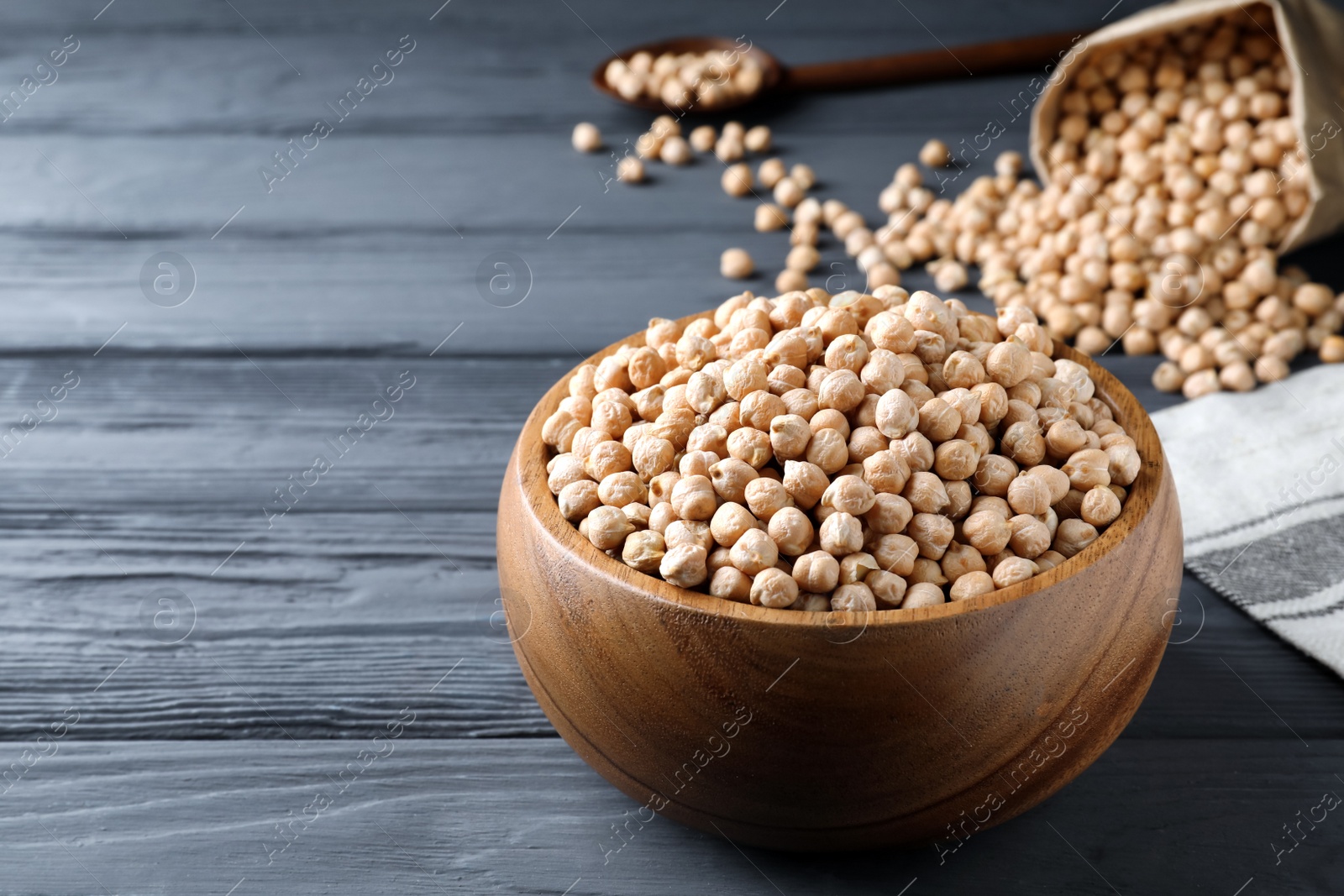 Photo of Raw chickpeas on black wooden table. Space for text