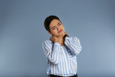 Image of Young woman suffering from neck pain on grey background