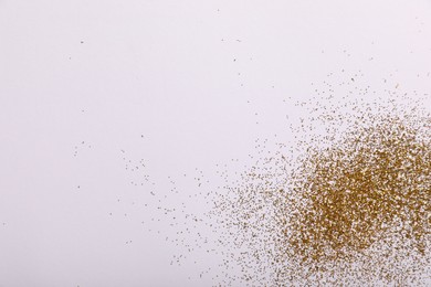 Photo of Shiny golden glitter on white background, top view