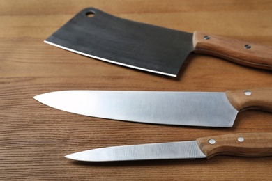Photo of Set of sharp kitchen knives on wooden table