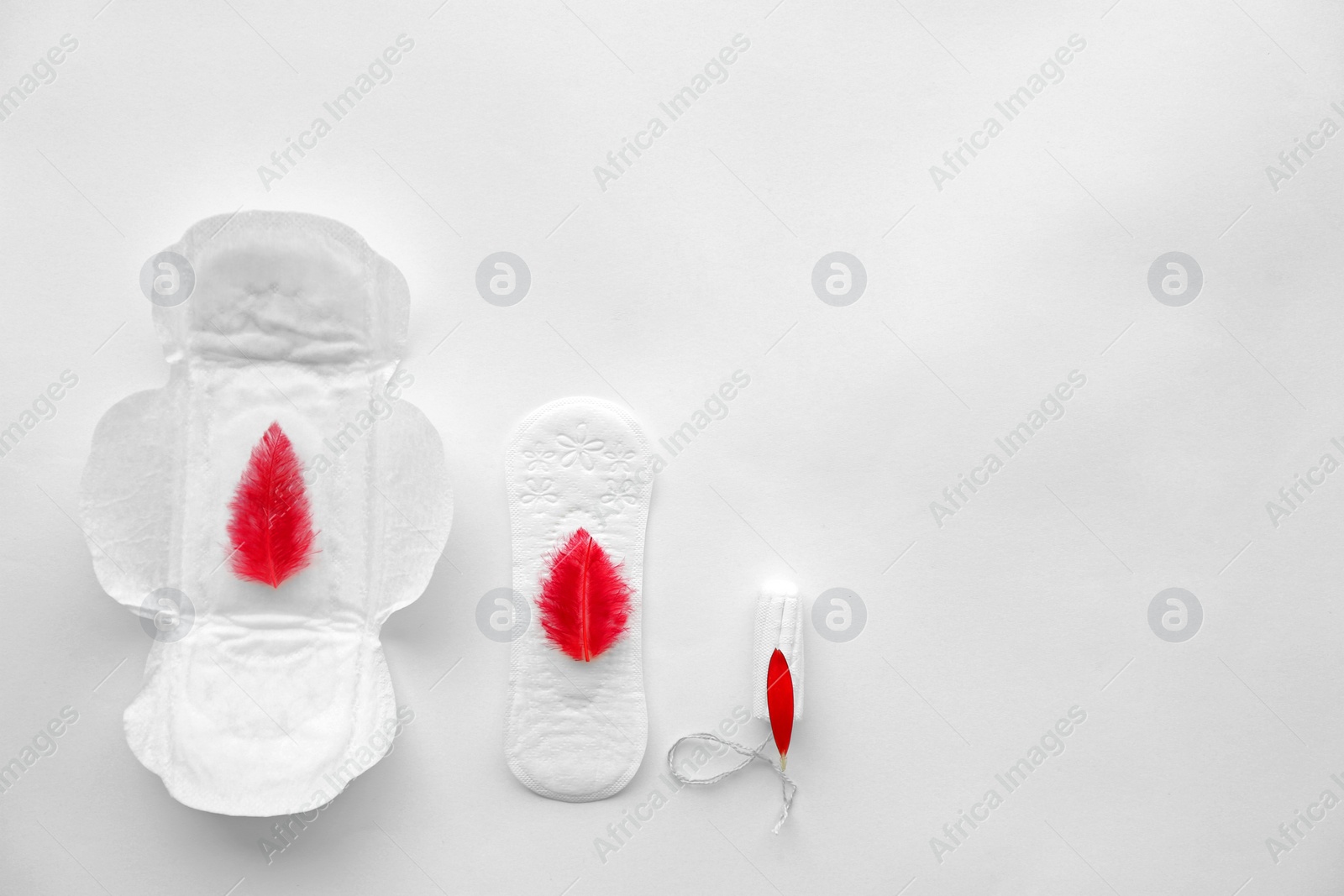 Photo of Flat lay composition with feminine hygiene items and red feathers on light background. Gynecological care