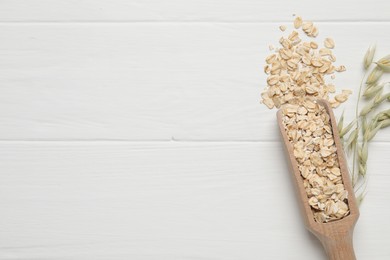 Photo of Scoop with oatmeal and florets on white wooden table, top view. Space for text