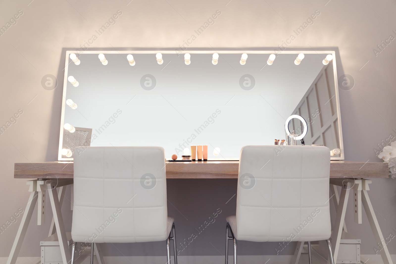 Photo of Modern mirror with light bulbs on dressing table in makeup room