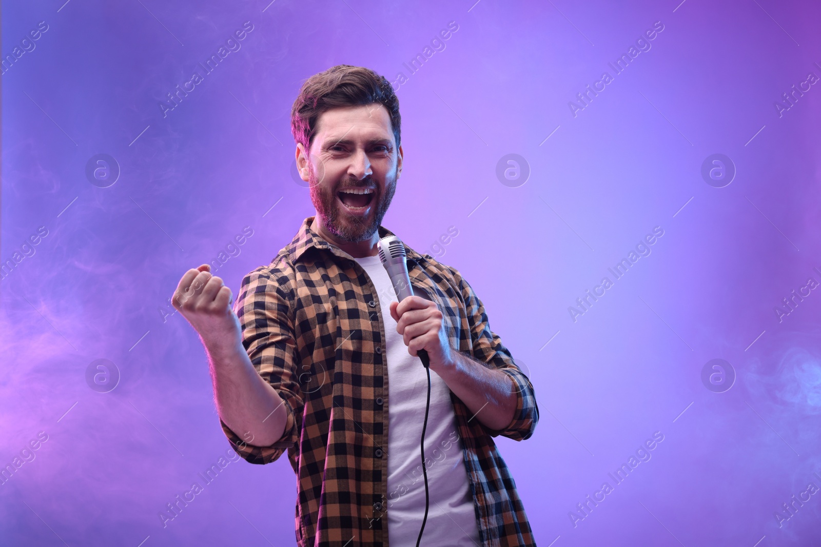 Photo of Handsome man with microphone singing in neon lights