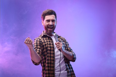 Photo of Handsome man with microphone singing in neon lights