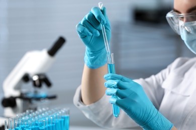 Photo of Scientist taking sample with dropper from test tube in laboratory, closeup