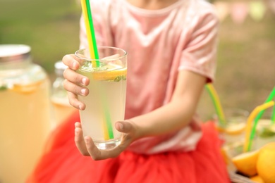 Photo of Little girl with natural lemonade outdoors, closeup