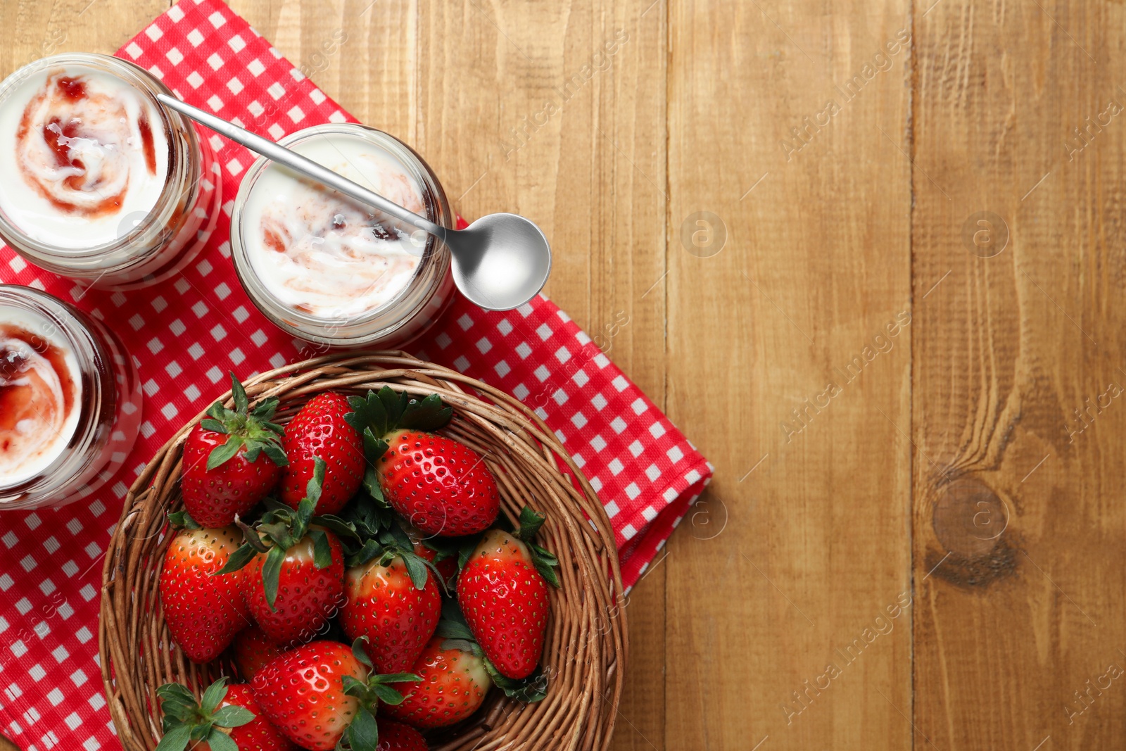 Photo of Tasty yoghurt with jam and strawberries on wooden table, top view. Space for text