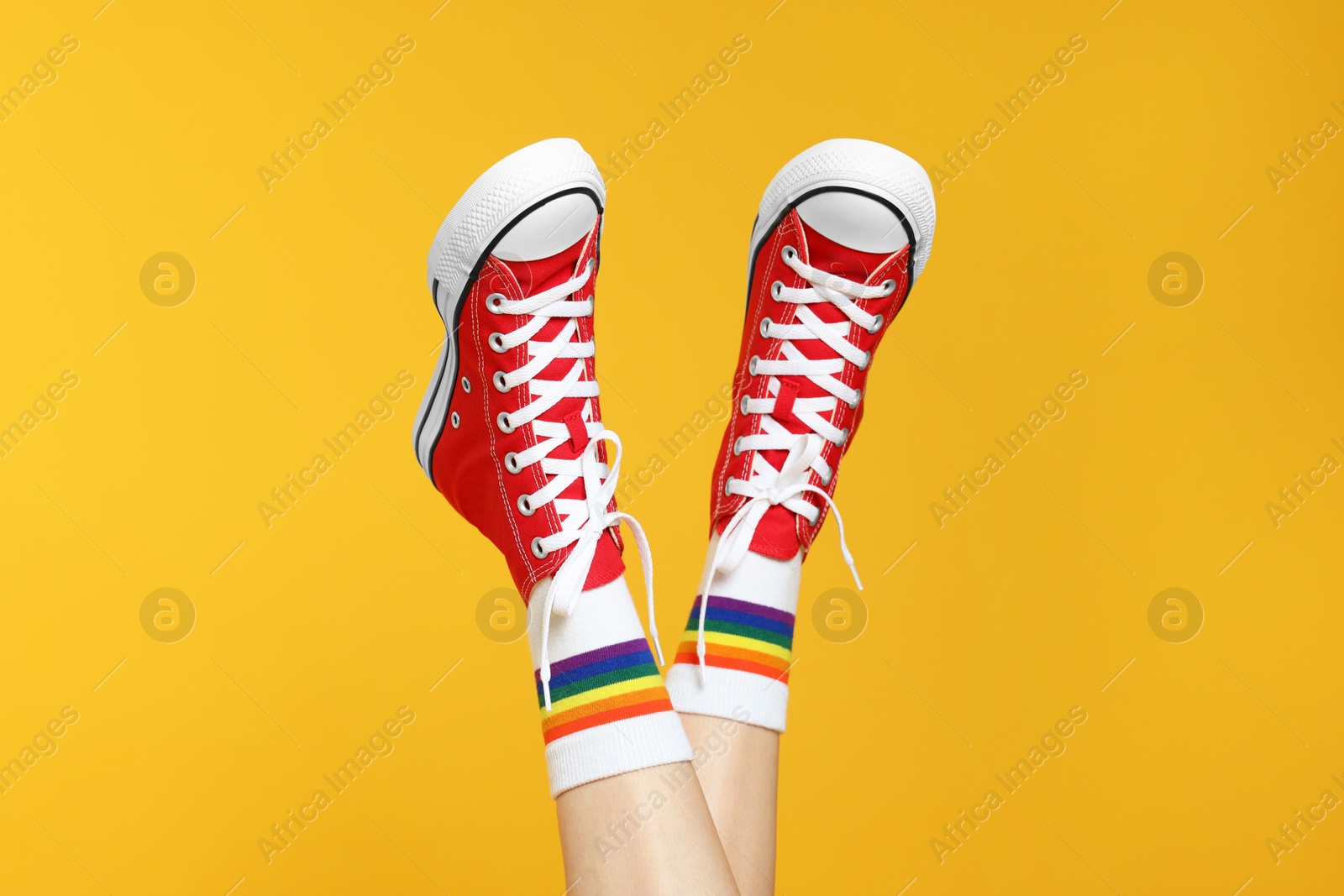 Photo of Woman in stylish gumshoes on yellow background, closeup. Space for text