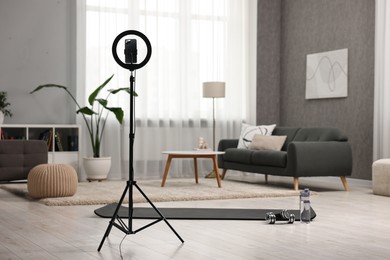 Photo of Ring light with smartphone and sports equipment at home
